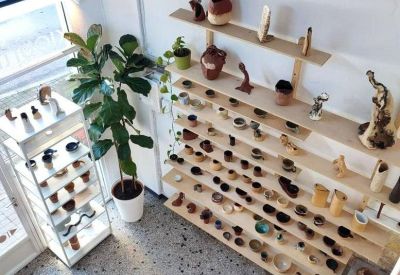 High-angle view of a bright office space with many ceramic objects on shelves and a potted fiddle-leaf fig.