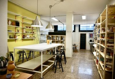 Coworking space featuring a large central table, black stools, and light wood storage units.