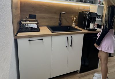 Compact office kitchenette with a coffee machine, microwave, and white cabinetry.