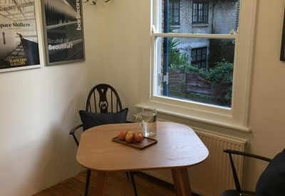 Sunny breakout corner with a small wooden table, plants, and a window overlooking greenery.