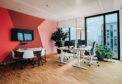 Modern office room with a red geometric feature wall and white minimalist desks.