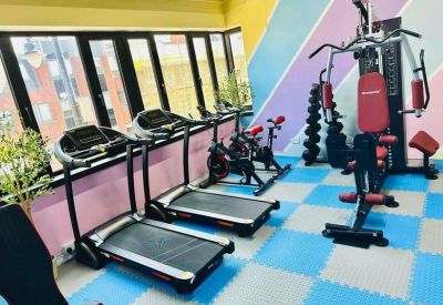 A vibrant gym area with treadmills, stationary bikes, and colorful checkered flooring.