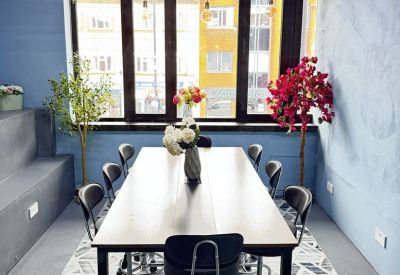 A long meeting table with high-backed chairs under hanging greenery and decorative lights.