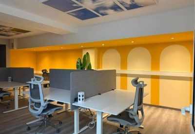 Modern open-plan office with yellow accent walls, ergonomic chairs, and cloud-themed ceiling panels.