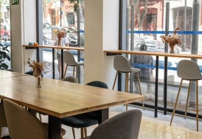 Large wooden meeting table in a sunlit room with floor-to-ceiling windows and street views.