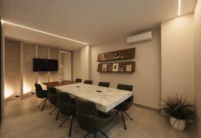 Minimalist hallway with glass partitions leading to a seating area with plants.
