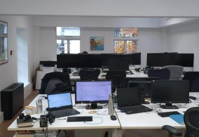 Office desks with computers in a bright room.