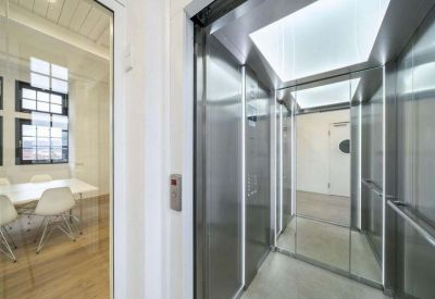 Narrow elevator hallway with glass doors and overhead lights.