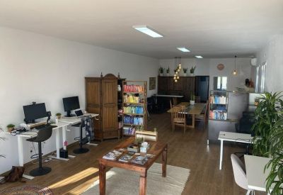 Spacious communal area with diverse seating, a large wooden table, and tall bookshelves.