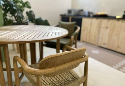 Communal dining area featuring a round wooden table and chairs with woven seats.