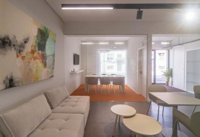 Lounge area with a grey sofa, coffee tables, and vibrant wall art.
