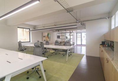 Spacious open-plan workspace with white desks and a lime green rug.