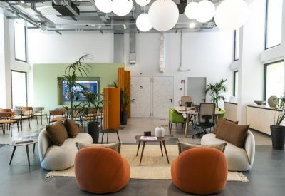 Spacious communal lounge with orange velvet armchairs, orb lighting, and potted plants.