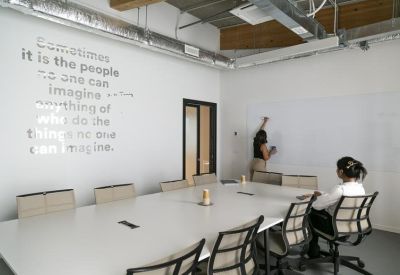 Bright conference room featuring an inspirational wall quote and a long white table.