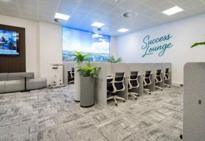 Spacious coworking area with modern workstations and Success Lounge wall graphic.