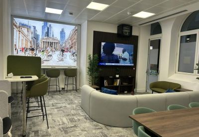 Breakout lounge with comfortable seating, a wall-mounted TV, and a scenic city mural.