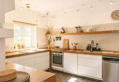 Modern white kitchen with wooden countertops, open shelving, and integrated appliances.