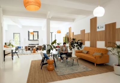 Bright communal lounge with a yellow sofa, wooden wall panels, and several seating areas.
