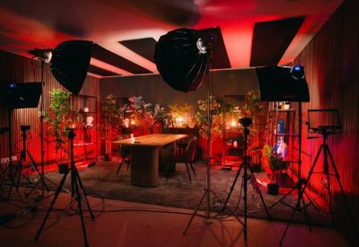 Production studio with professional lighting, cameras, and a long wooden meeting table.