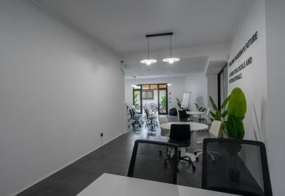 Bright open-plan office with modern white desks and black mesh chairs.
