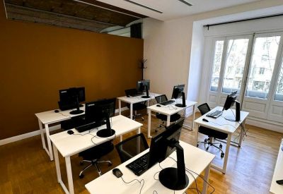 Bright coworking area with white desks and an accent wall in warm ochre.