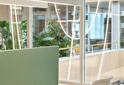 White desk setup with ergonomic chair and large windows overlooking lush plants.
