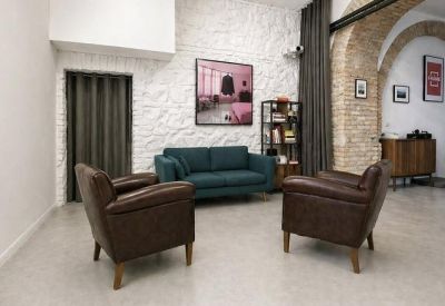 Lounge area with a teal sofa and leather armchairs against a white textured wall.