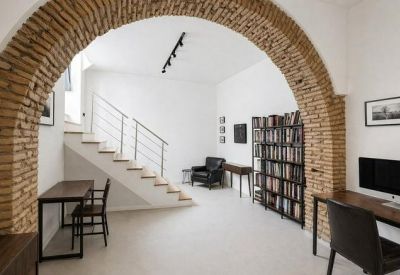 Bright office space featuring a brick archway, staircase, and a lounge chair in the background.