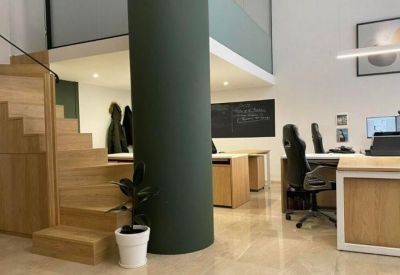 Modern wooden staircase next to a minimalist open-plan workspace.