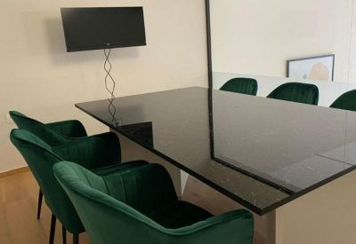 Meeting area with a sleek black table and emerald green velvet chairs.