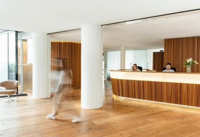 Modern reception area featuring wood-paneled walls, matching desk, and warm timber flooring.
