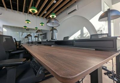 Long wooden desk with ergonomic chairs and modern overhead lighting.