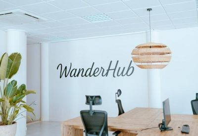 Modern workspace with WanderHub logo, potted plants, and ample natural light.