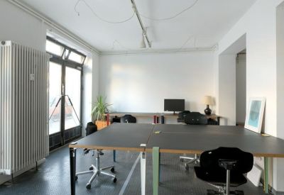 Natural light fills the shared workspace with black desks at 63, Stettiner Straße.