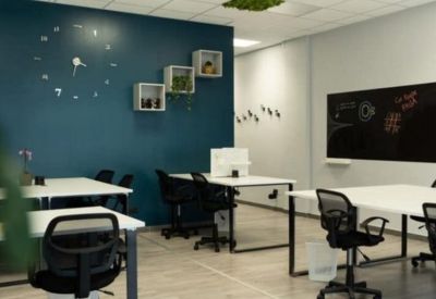 Modern open-plan office with white desks, ergonomic chairs, and a dark blue feature wall.