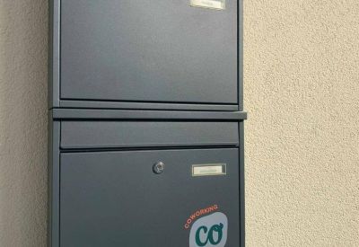 Communal kitchen area with black cabinetry, a wooden table, and natural light from a large window.