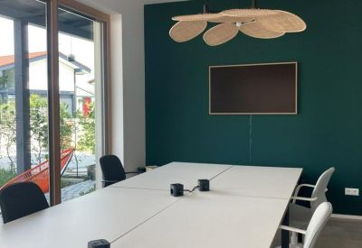 Meeting room with a white conference table, green accent wall, and large windows.