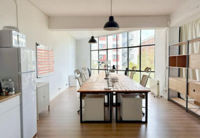 Long shared wooden desk with ergonomic white chairs and city views.