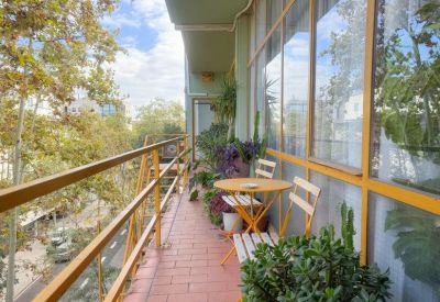 Lush outdoor balcony with potted plants, a small table, and chairs.