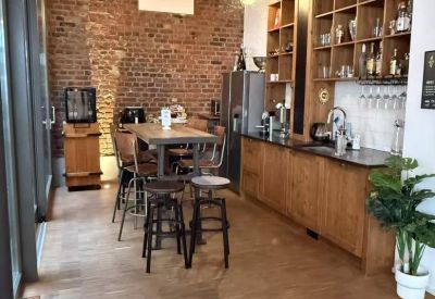 Communal kitchen and break area with high wooden tables, shelving, and brick feature wall.