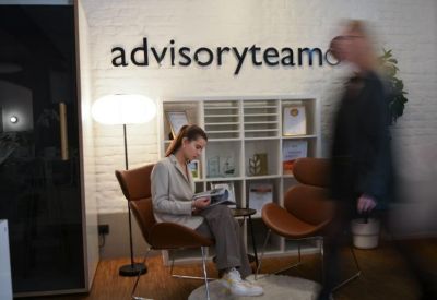 Reception area with brown leather lounge chairs and a bookshelf under building signage.