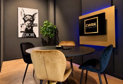 Modern communal lounge area with a round table, velvet chairs, and bold animal wall art.