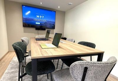 Close-up of a conference table with laptops and a video conferencing display.