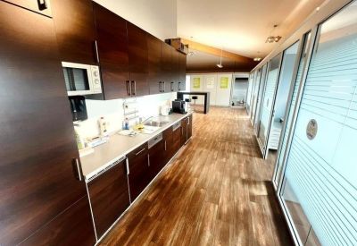 Modern office kitchen with dark wood cabinets and a long breakfast bar.