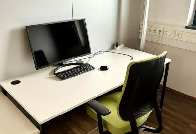 Single workstation with dual monitors and a floor lamp by a large window.