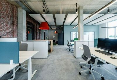 Bright open-plan office with brick accent wall and colorful pendant light.