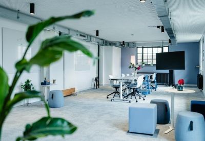 Spacious meeting room with white tables and light blue lounge seating.