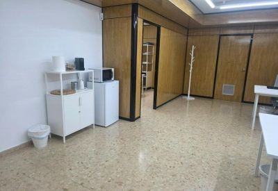 Communal kitchen area with a white cabinet, mini-fridge, microwave, and wood-paneled walls.