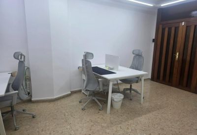 Private office featuring white desks and grey ergonomic chairs against a wood-paneled door.