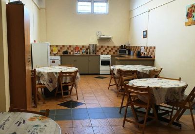 Communal kitchen with tables and wooden chairs.